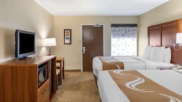 Habitación de hotel con dos camas, televisión, escritorio con lámpara y puerta que da a otra habitación.