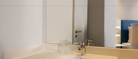 A modern bathroom with a white sink, a mirror, and a door.