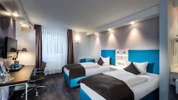 A hotel room with two beds, a desk, a chair, a TV, and a window with curtains.