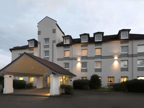 Ein mehrgeschossiges Hotel mit überdachter Eingangspartei, zahlreichen Fenstern und einer gut beleuchteten Fassade.