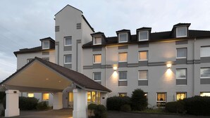 A multi-story hotel with a covered entrance, multiple windows, and a well-lit facade. - ibis Styles Cologne Airport Troisdorf (Troisdorf)