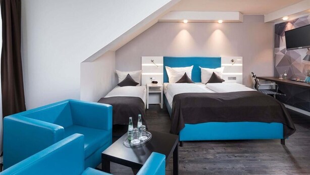 Habitació d'hotel moderna amb dos llits, un escriptori i una zona de seients.