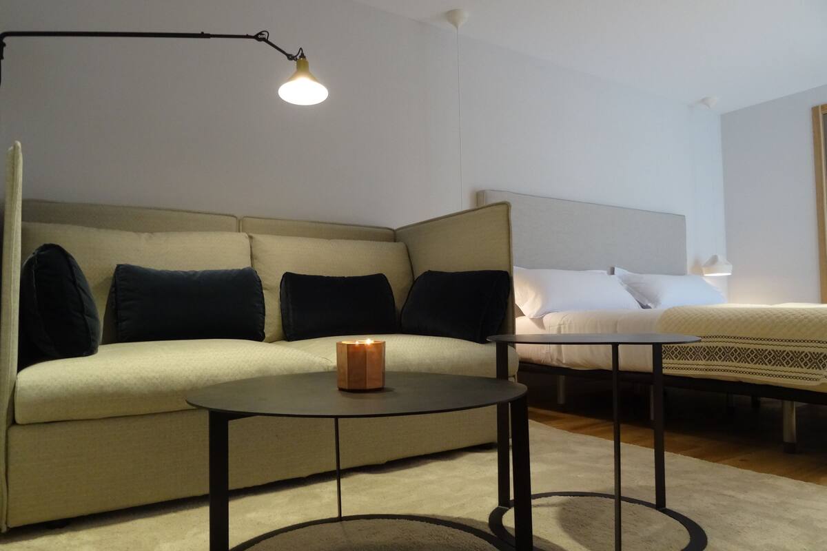 Une chambre d’hôtel moderne, équipée d’un canapé, d’une table de chevet et d’une lampe.