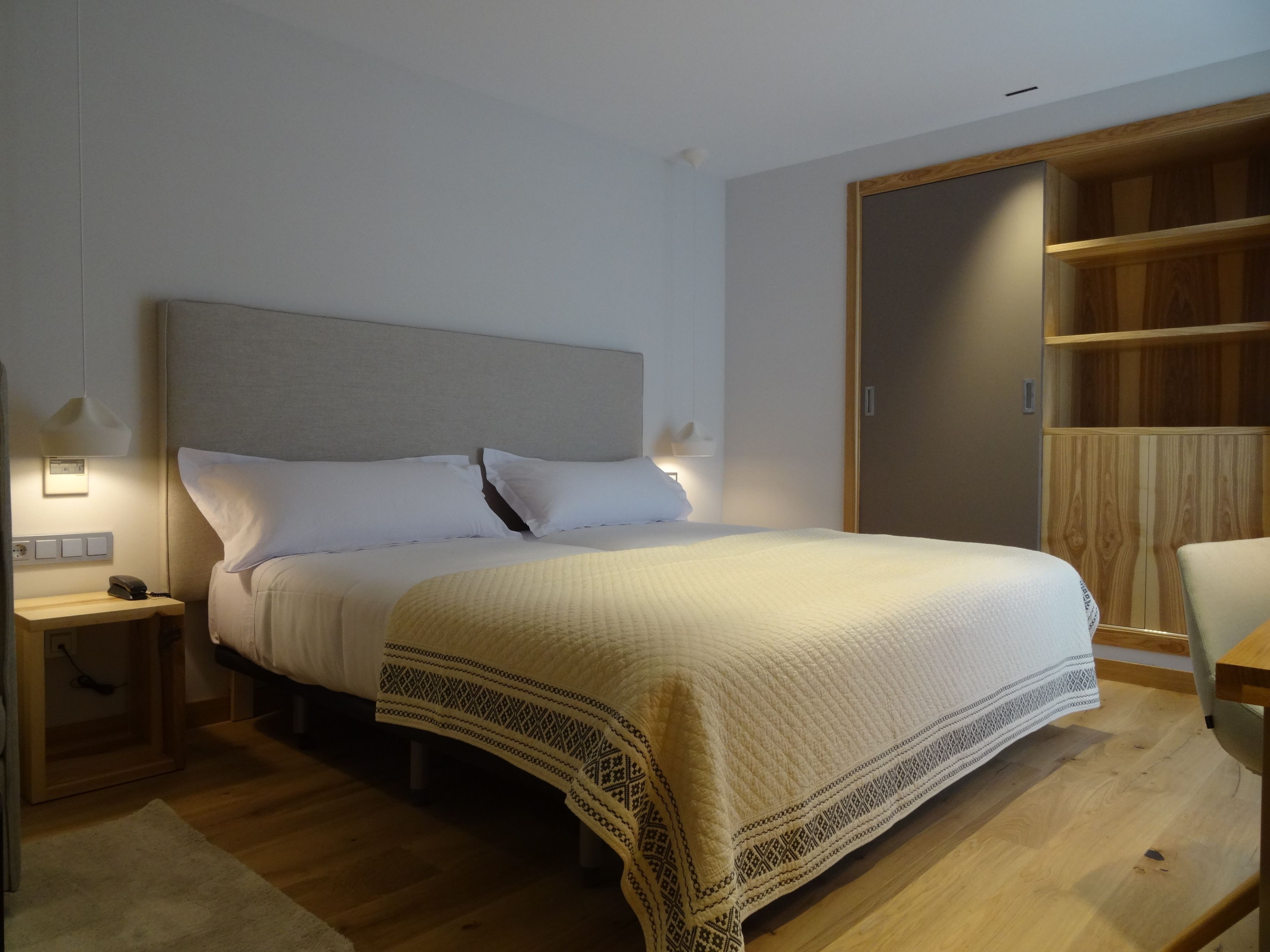 Un dormitorio con una cama grande, mesitas de noche, un armario de madera y una silla.