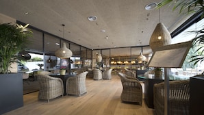 A modern restaurant interior with wicker furniture, pendant lighting, and a menu stand. - Hotel Zenit Sevilla (Seville)