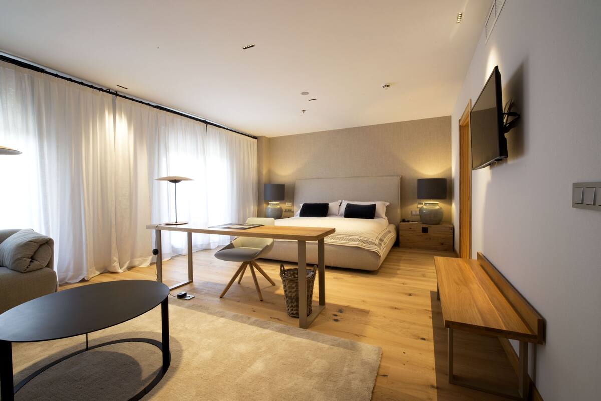 Une chambre moderne avec un grand lit, des lampes de chevet, un bureau et une chaise.