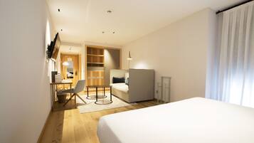 Ein Hotelzimmer mit Bett, Schreibtisch mit Stuhl, Kleiderschrank und kleinem Tisch.
