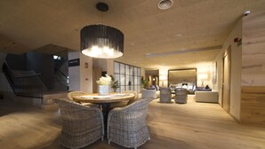 A spacious, modern hotel lobby with a round dining table, wicker chairs, and a large pendant light. - Hotel Zenit Sevilla (Seville)