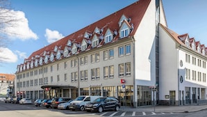 A multi-story hotel with a red-tiled roof, a restaurant on the ground floor, and several parked cars. - ibis Erfurt Altstadt (Erfurt)
