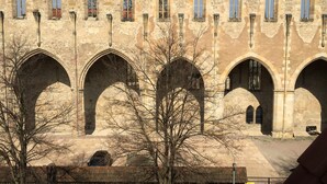 Un edificio histórico de piedra con varios ventanales de arco y un patio.