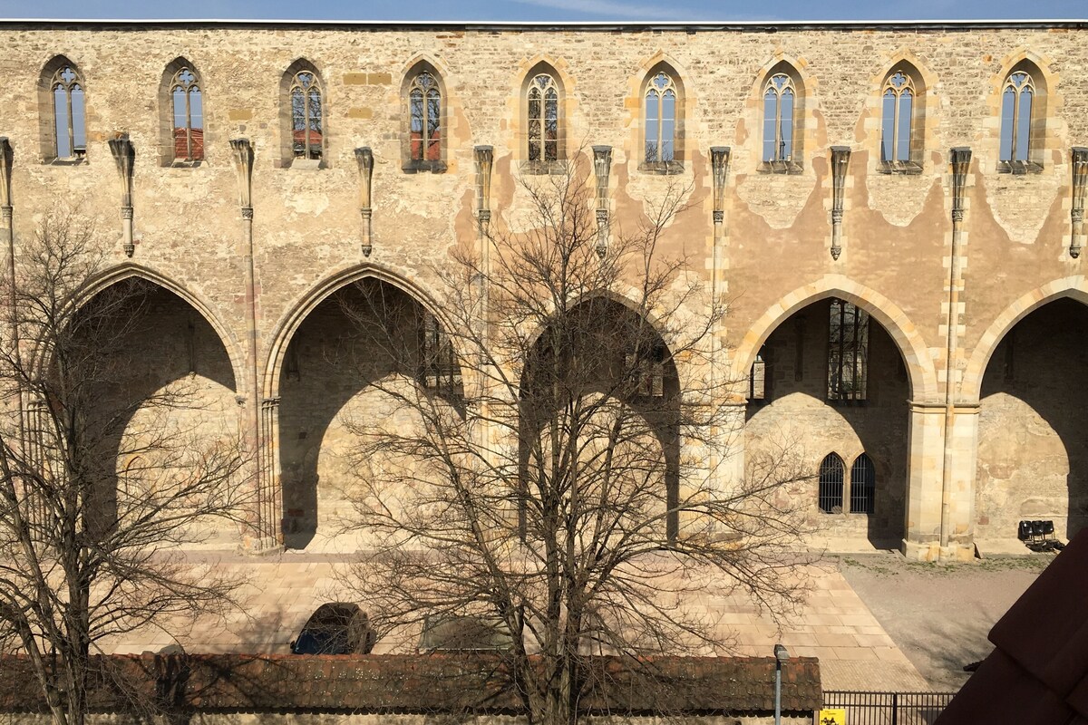 Un edificio histórico de piedra con varios ventanales de arco y un patio.