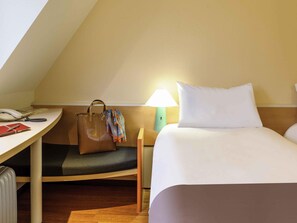 A hotel room with a desk, a telephone, a lamp, a bed, and a suitcase. - ibis Erfurt Altstadt (Erfurt)
