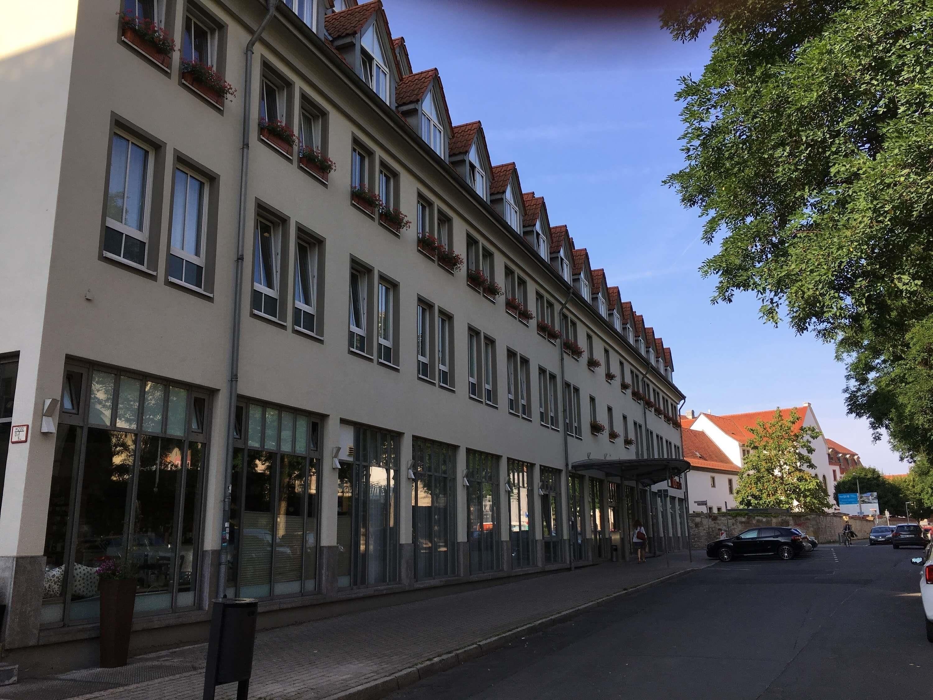 Un edificio a più piani con ampie finestre e uno spazio esterno coperto.