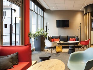 Un espace de détente moderne comprenant un canapé, des fauteuils, une table et une grande plante en pot.