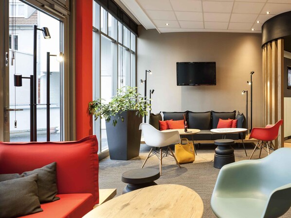 A modern lounge area with a sofa, chairs, a table, and a large potted plant. - ibis Erfurt Altstadt (Erfurt)