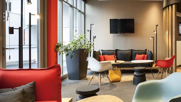 A modern lounge area with a sofa, chairs, a table, and a large potted plant. - ibis Erfurt Altstadt (Erfurt)