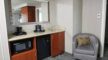 A compact kitchenette with a microwave, coffee maker, and sink.
