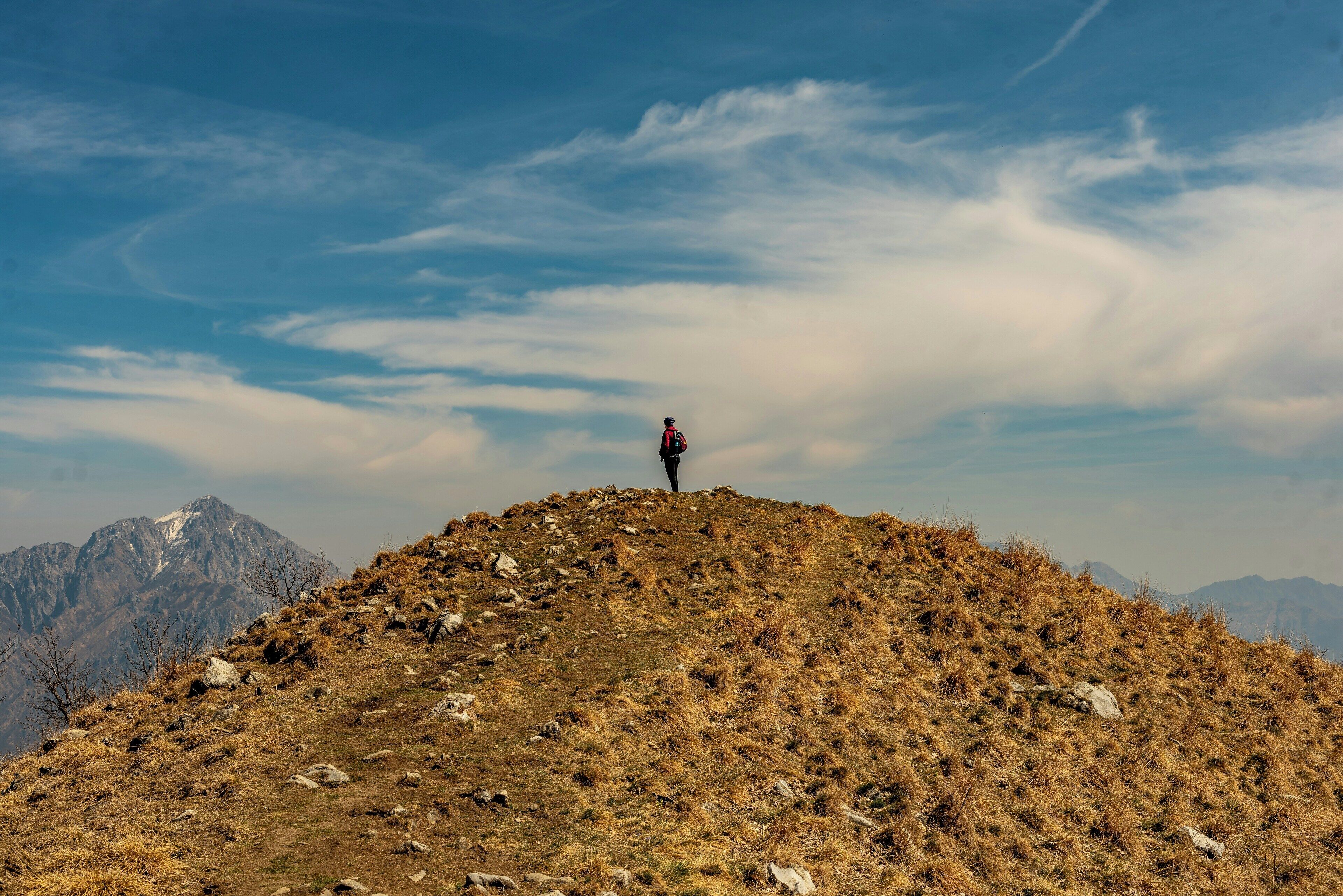 A person standing on a grassy hill with mountains in the background.