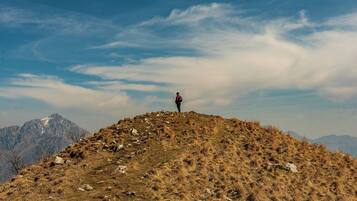 A person standing on a grassy hill with mountains in the background.