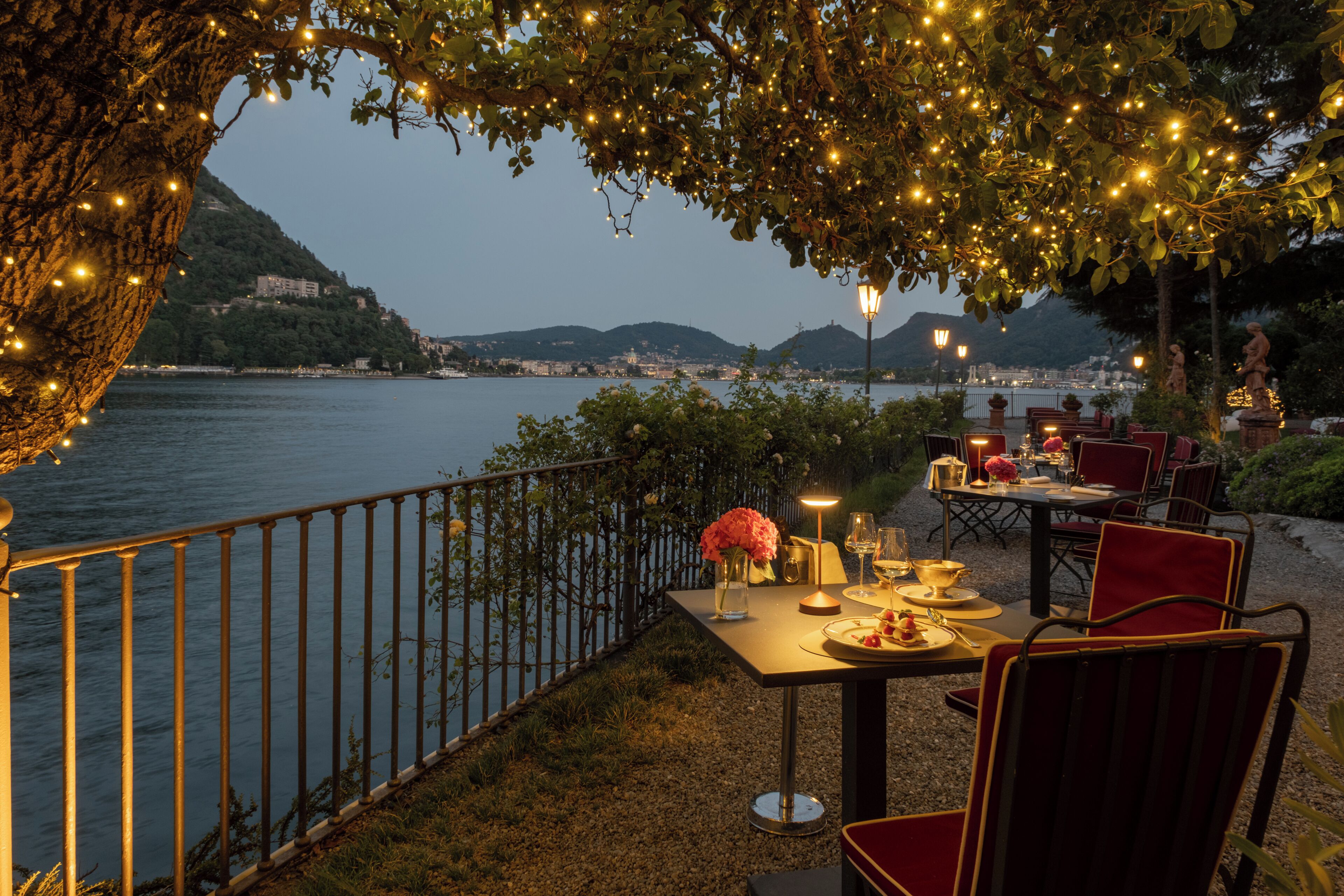 Een terras met eethoek voor twee personen, met uitzicht op een waterpartij en een stadsgezicht.