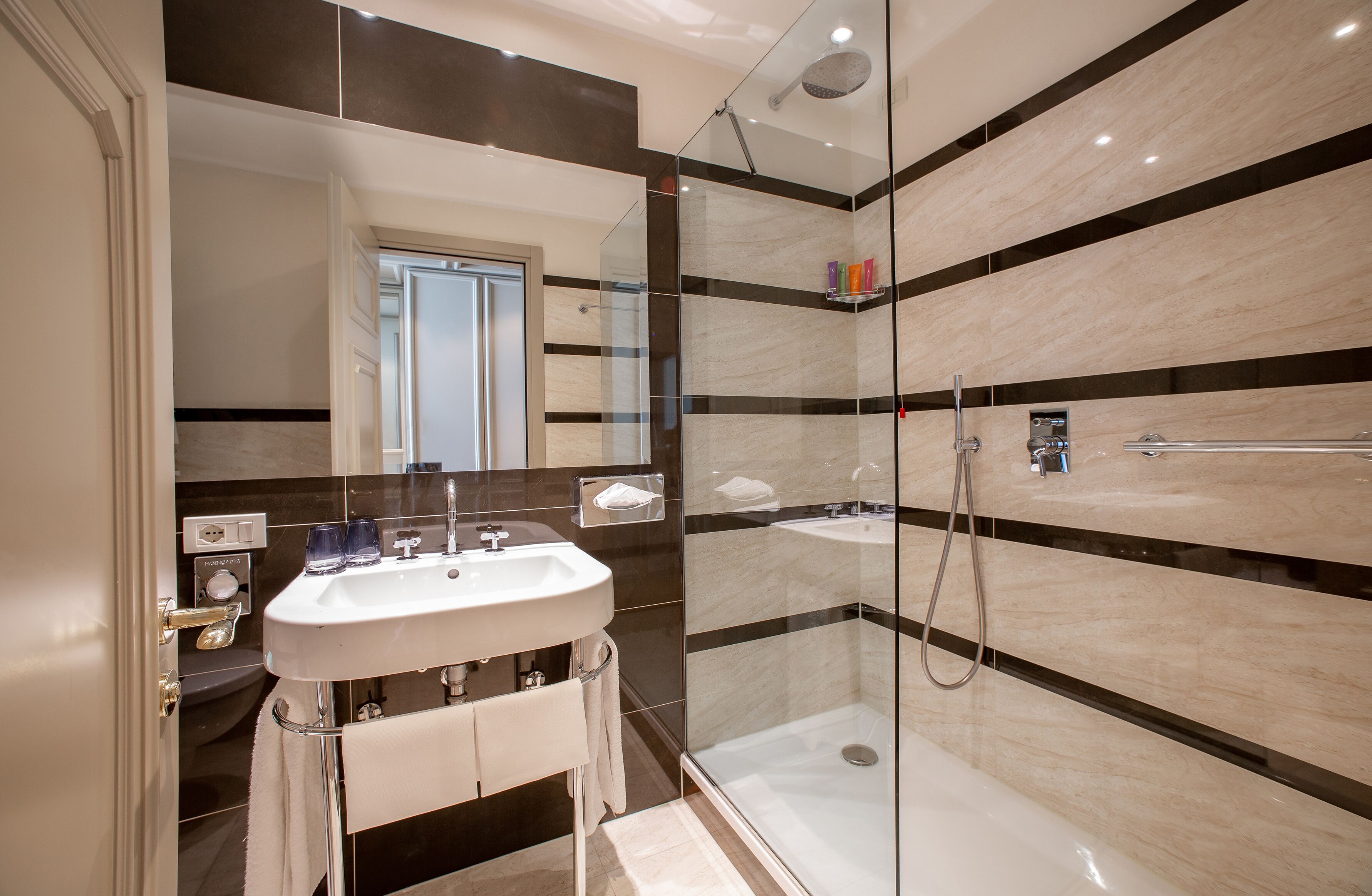 A modern bathroom with a glass-enclosed shower, a white sink, and a mirror.