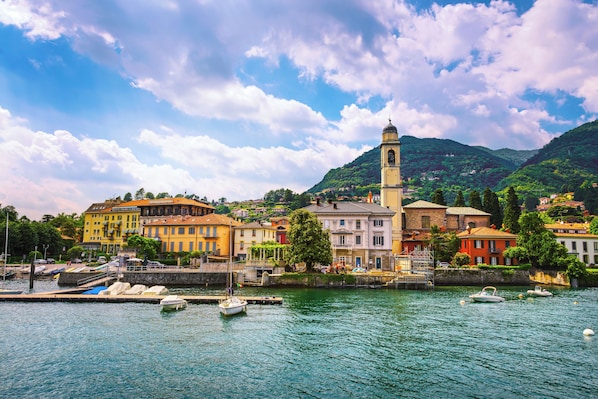 A waterfront town with buildings, a prominent tower, and boats docked along the shore.