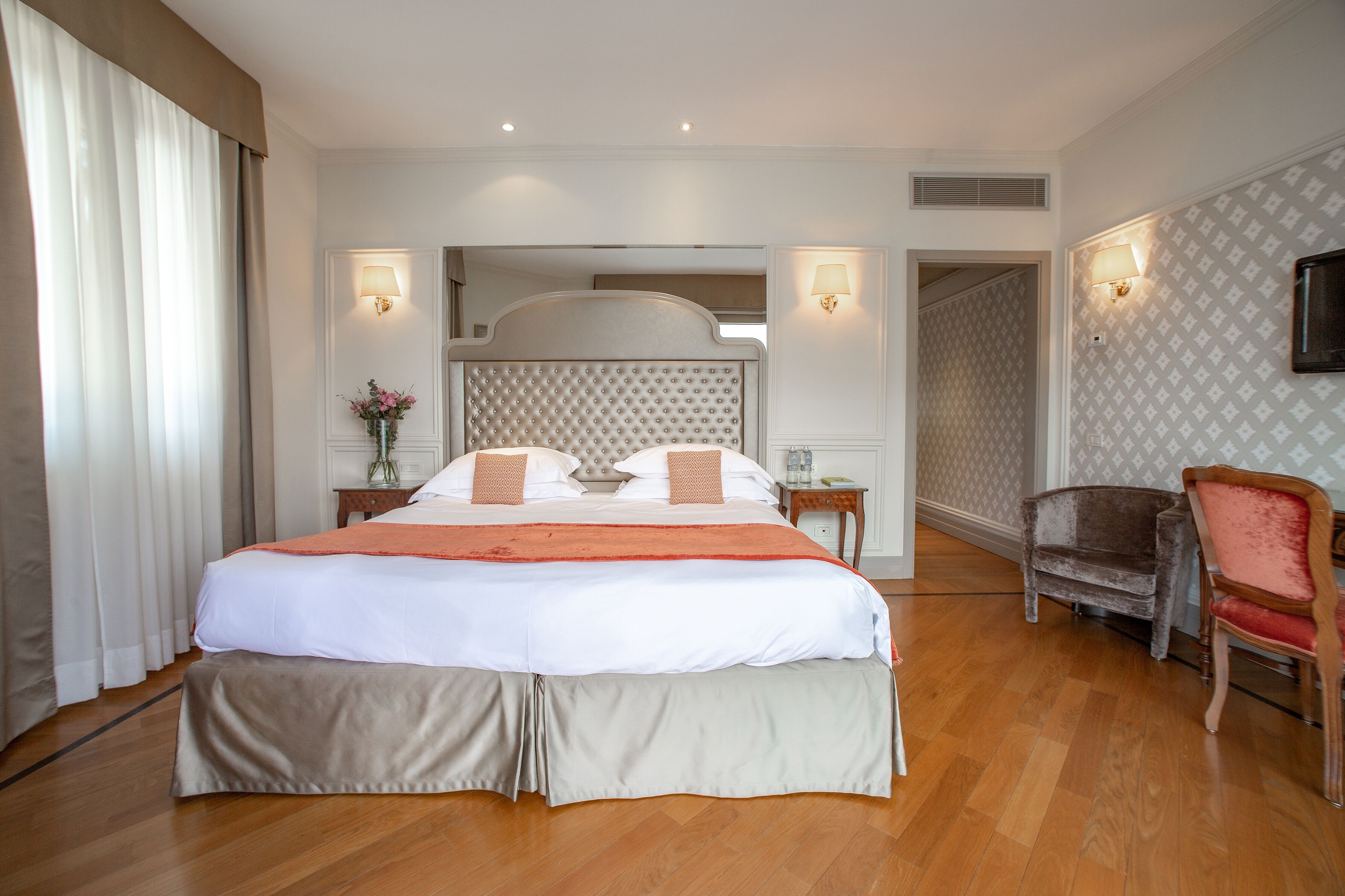 Ein Hotelzimmer mit einem großen Bett, einem Sessel, einem Nachttisch und einer Lampe.