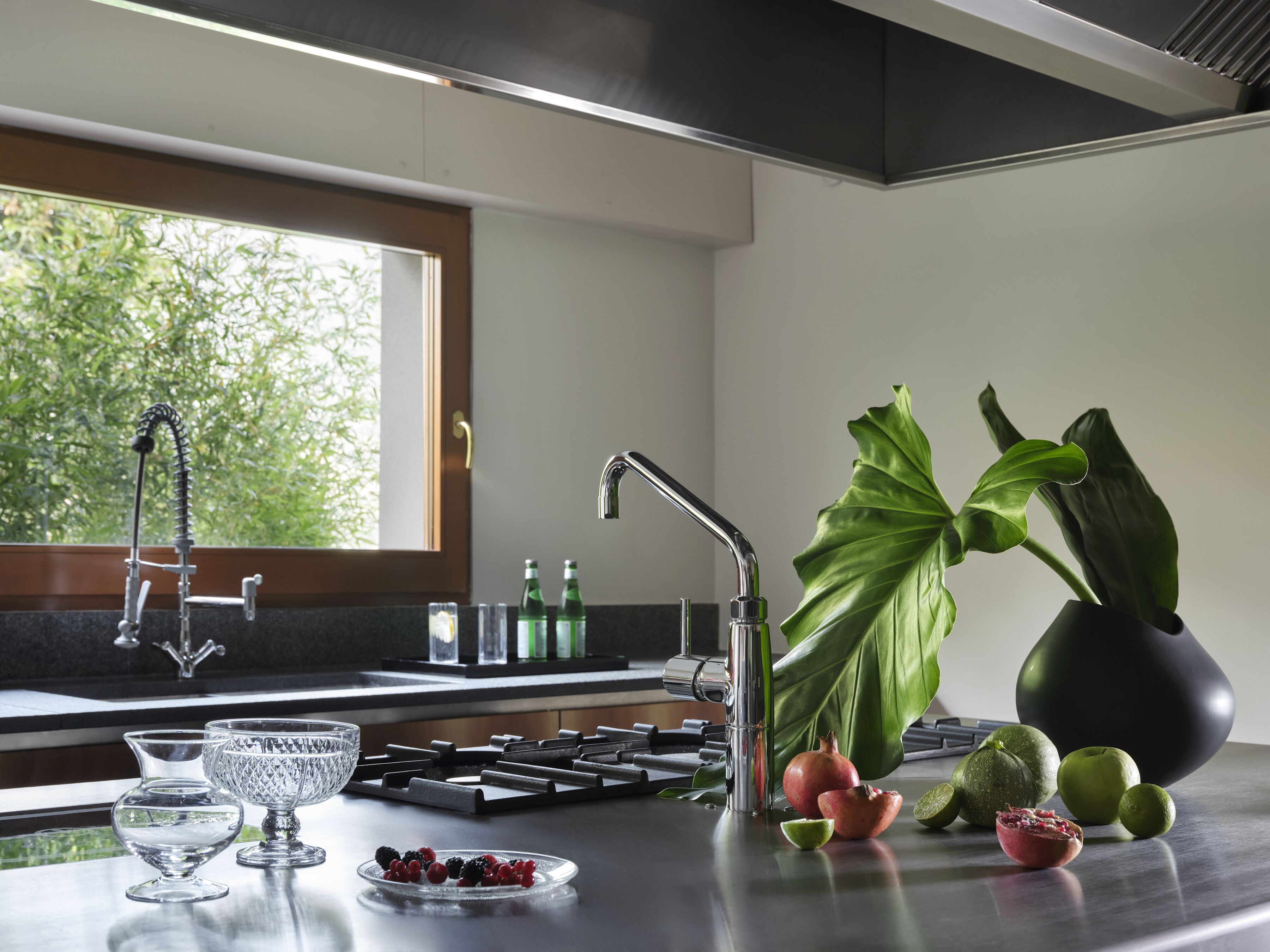 Una cocina moderna con encimera de acero inoxidable, cocina integrada y ventana con vistas a zonas verdes.
