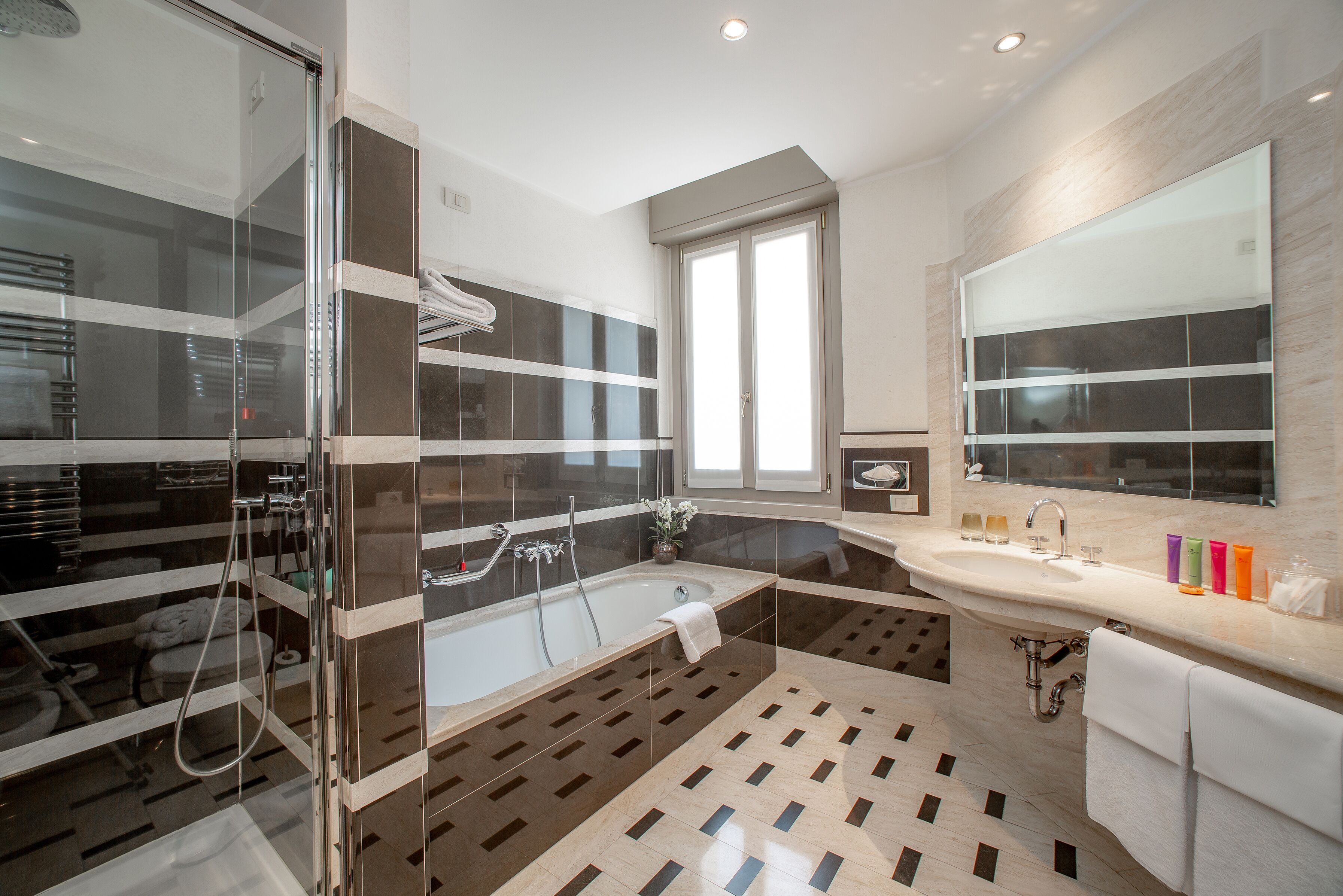 Un baño moderno con ducha envuelta en vidrio, una bañera independiente y un tocador con un espejo grande.