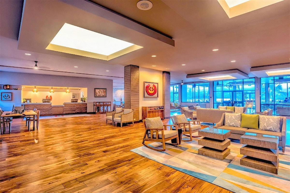 A spacious lobby with a reception desk, seating area, and large windows.