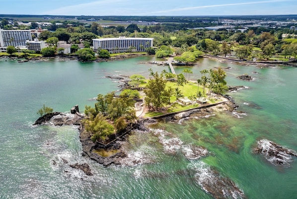 An aerial view of a coastal area with a small island featuring a dock and lush greenery.