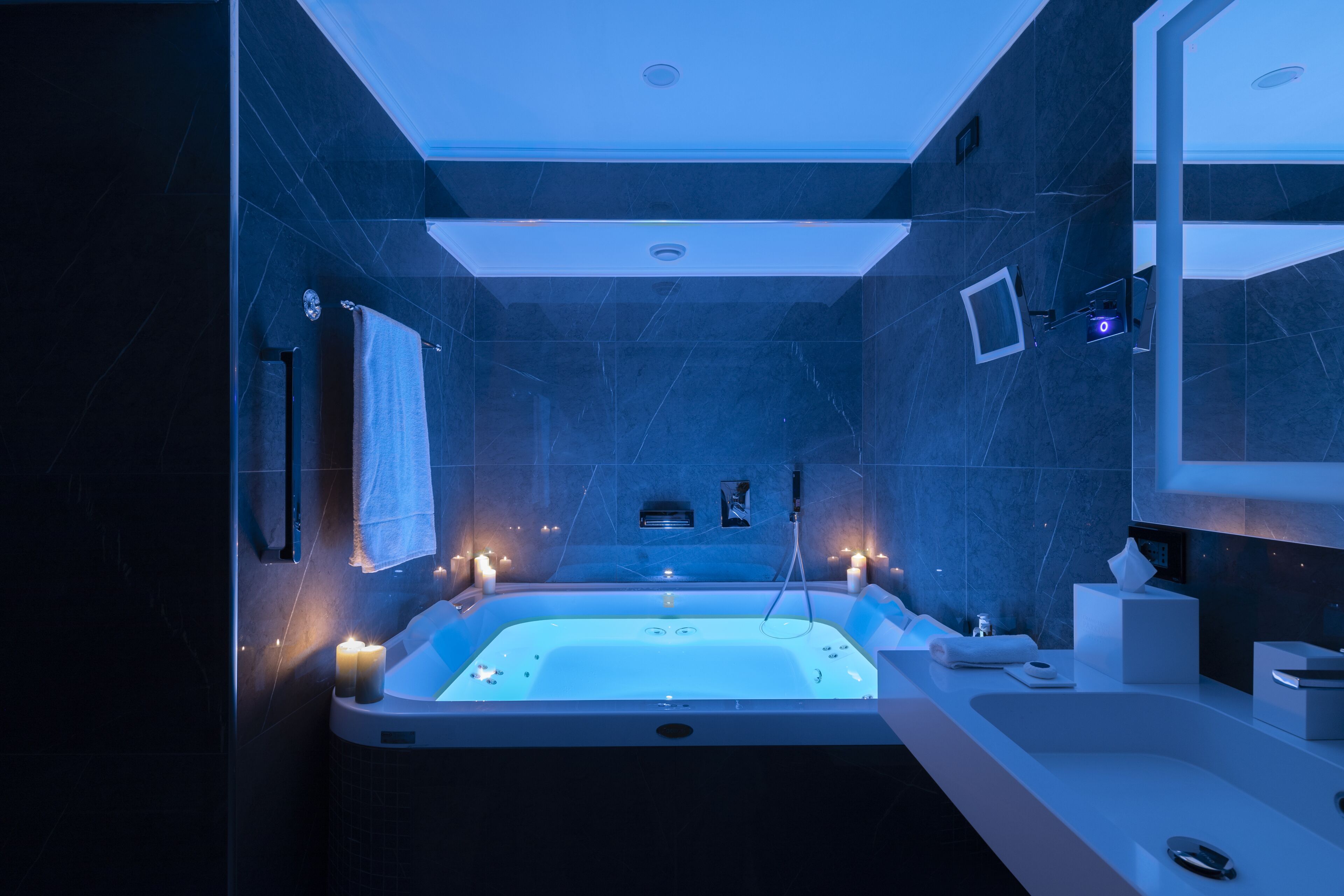 A modern bathroom with a large bathtub, a vanity with a mirror, and a wall-mounted heater.