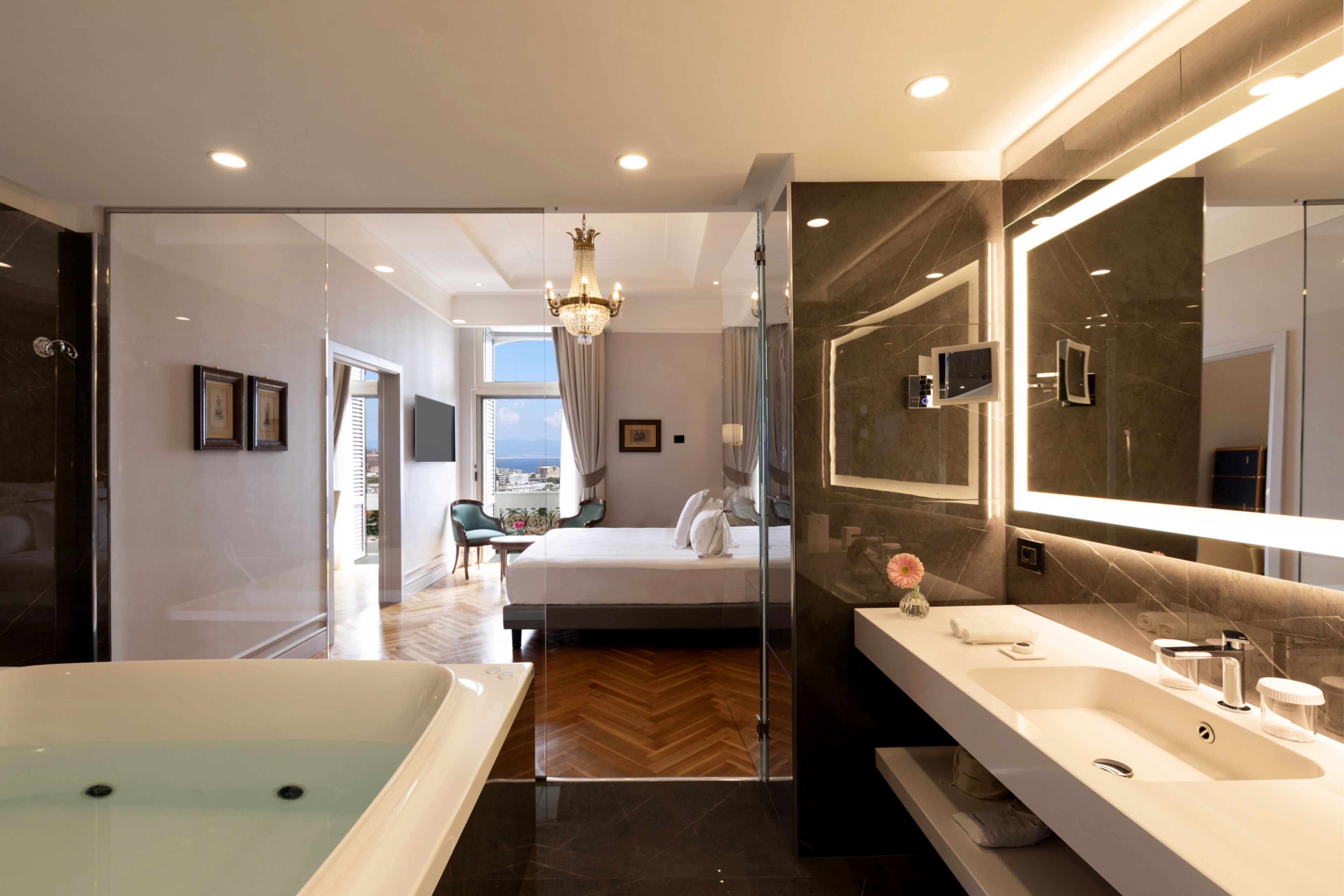Una camera d'albergo moderna con un letto grande, un bagno in vetro e vista sulla città.
