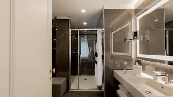 A modern bathroom with a glass shower enclosure, a large mirror, and a vanity with a sink and towel rack.
