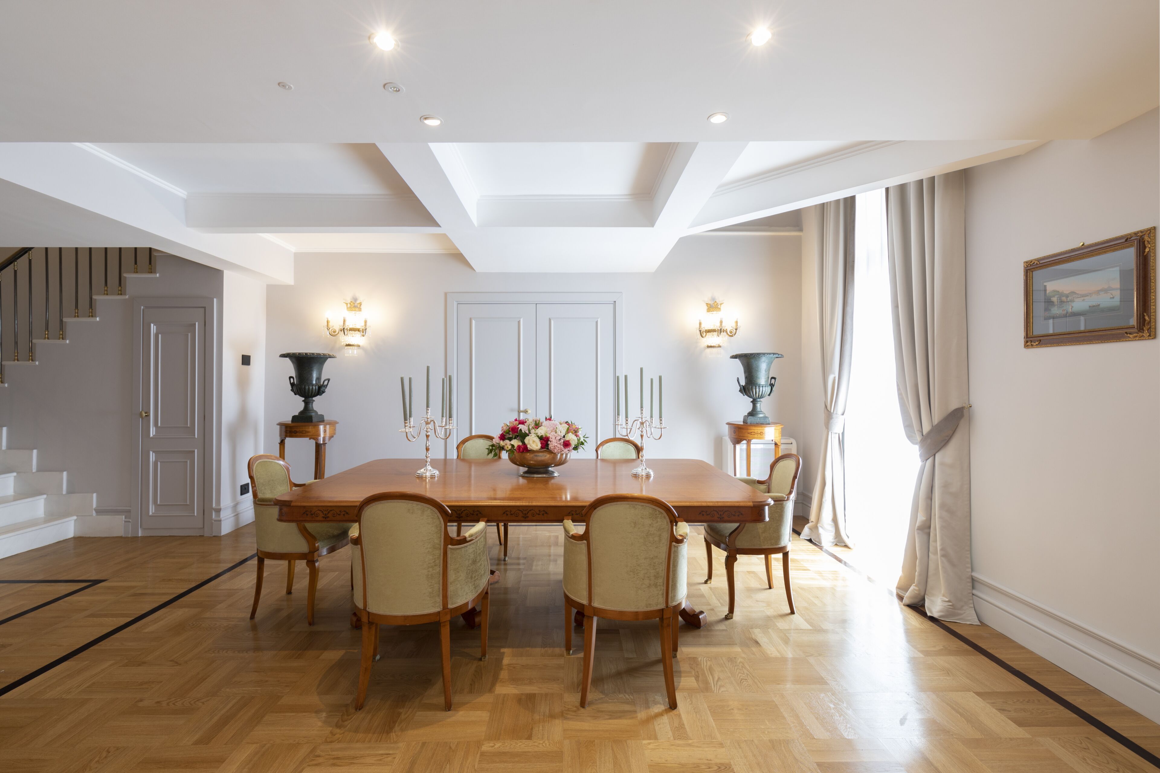 A dining room with a large wooden table, six chairs, and a chandelier.
