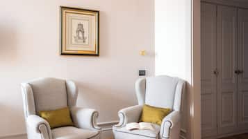 A room with two grey armchairs, one with a gold cushion, and a framed picture on the wall.