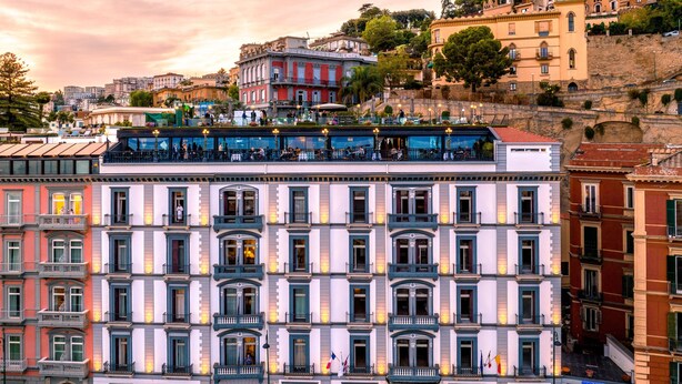 Ein mehrstöckiges Hotel im klassischen europäischen Stil, mit Balkonen und einem zentralen Eingang.
