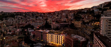A cityscape at dusk with a prominent building featuring a large, illuminated facade.