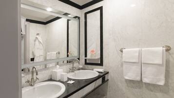 A modern bathroom with two sinks, a large mirror, and a towel rack.