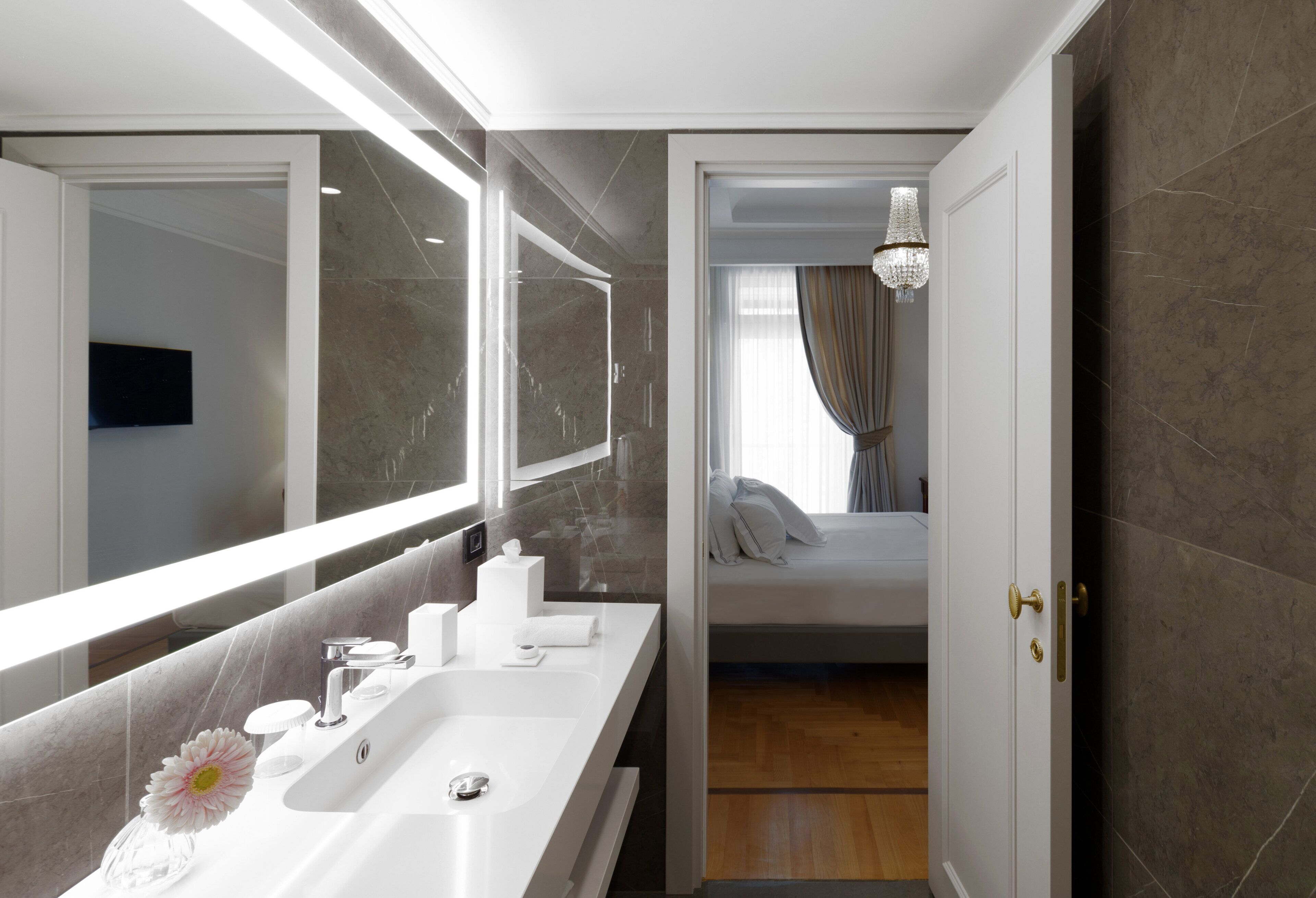 Une salle de bain moderne avec un grand miroir, un lavabo blanc et un espace douche.