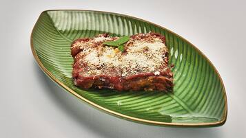 A plate with a slice of meat topped with cheese and herbs.