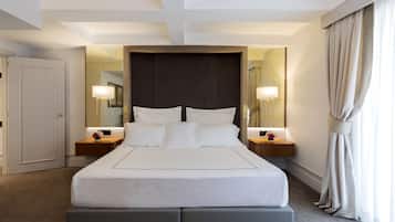 A hotel room with a large bed, two bedside tables, a headboard, and a mirror.