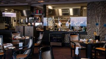 A restaurant with a bar area, multiple seating arrangements, and a visible kitchen in the background.