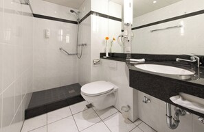 A modern bathroom with a white toilet, a sink, and a shower. - Leonardo Hotel Heidelberg (Heidelberg)