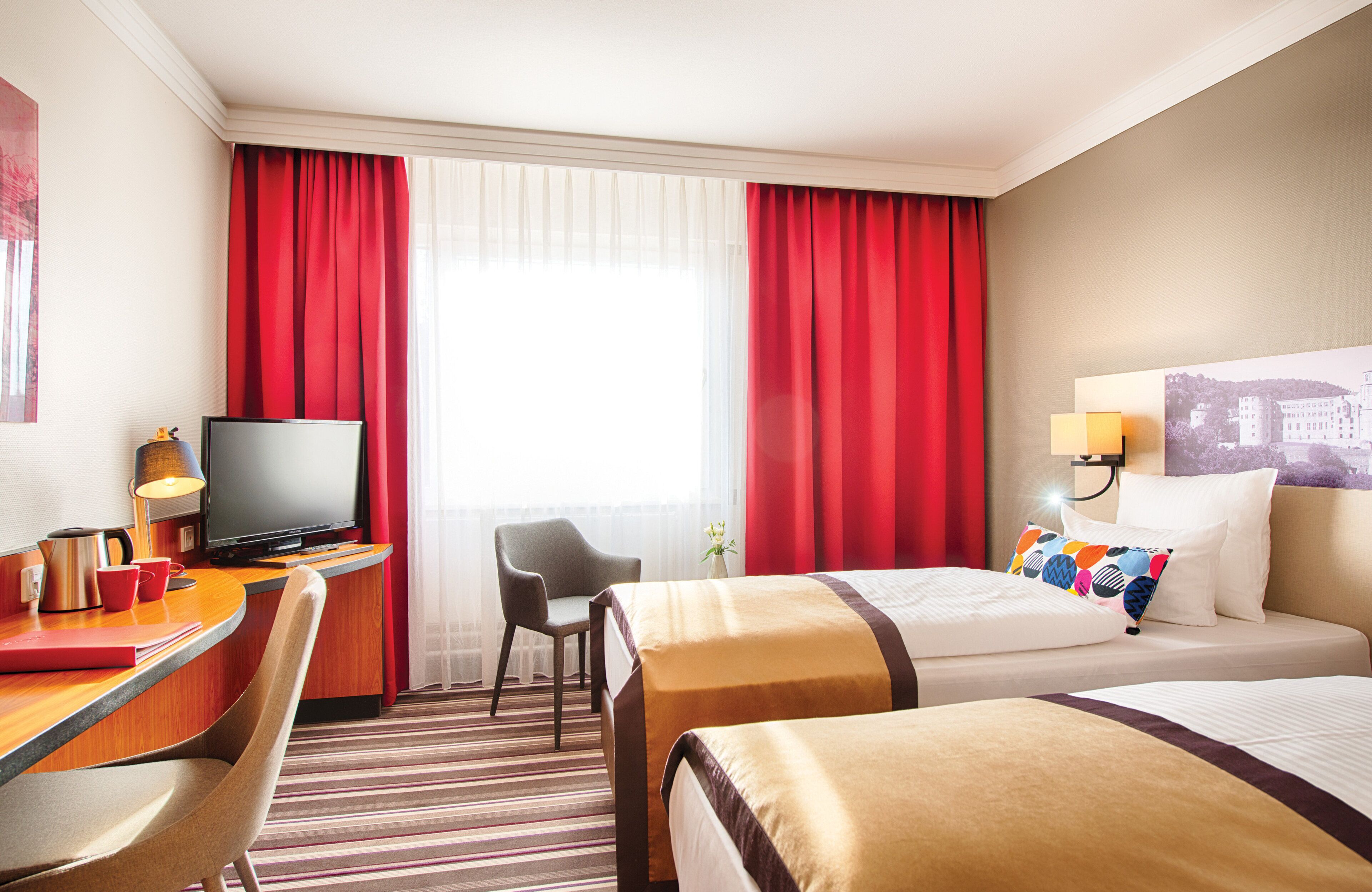 A hotel room with two beds, a desk with a television, and a chair.