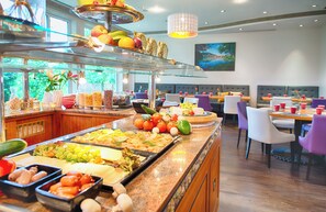 A buffet with various food items and a seating area with tables and chairs. - Leonardo Hotel Heidelberg (Heidelberg)