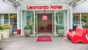 The exterior of the Leonardo Hotel with a glass entrance, red chairs outside, and a red carpet leading to the entrance. - Leonardo Hotel Heidelberg (Heidelberg)