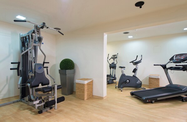 A gym with a treadmill, elliptical, and weight machine. - Leonardo Hotel Heidelberg (Heidelberg)