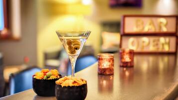 Un bar con una copa de martini y dos fuentes pequeñas de aperitivos en la barra.