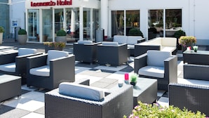 An outdoor seating area with wicker furniture and potted plants in front of a hotel entrance. - Leonardo Hotel Heidelberg (Heidelberg)